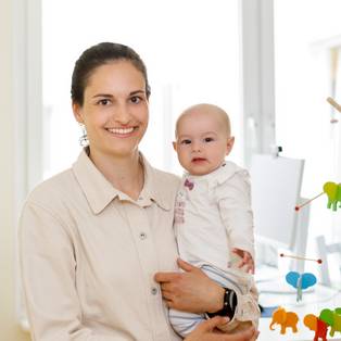 Foto einer Mutter mit ihrem Baby auf dem Arm in einem Büro der Charité