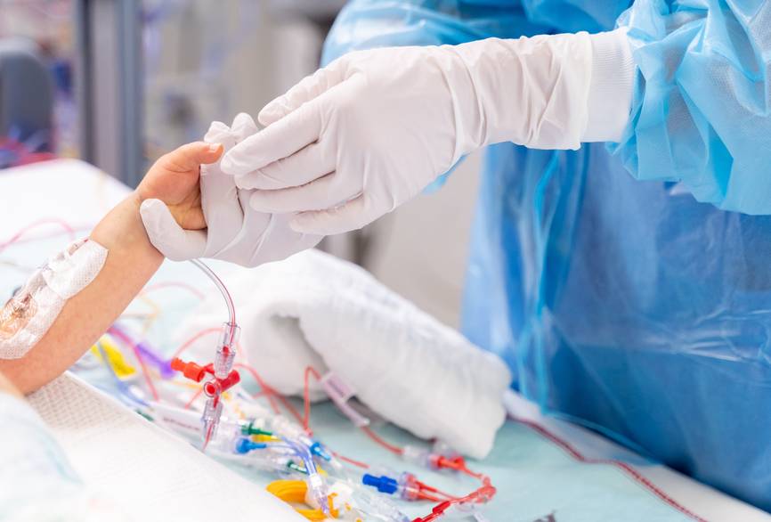 Eine Pflegefachkraft hält eine Kinderhand auf einer Intensivstation am CVK