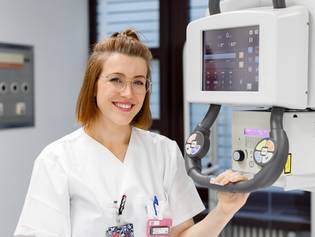 Eine Mitarbeiterin der Radiologie steht neben einem Röntgengerät