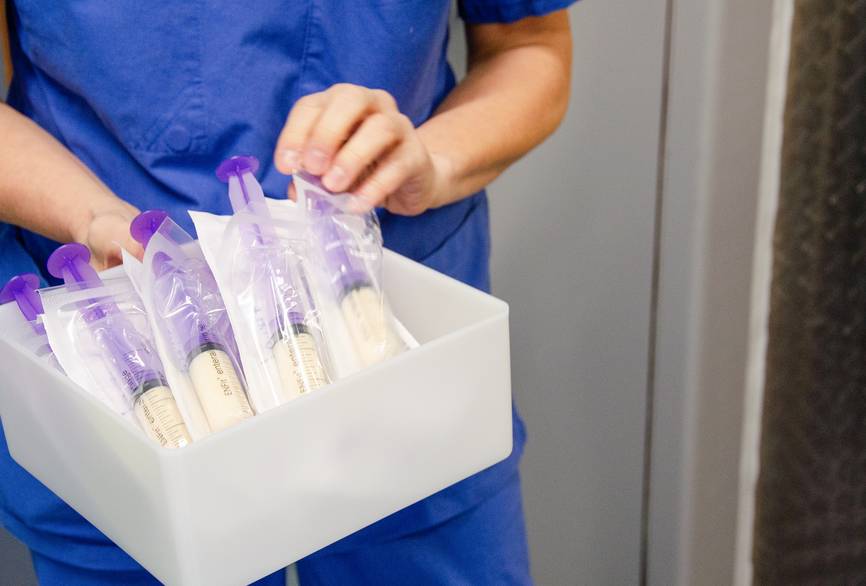 Eine Person hebt eine Box mit Ernährungsspritzen.