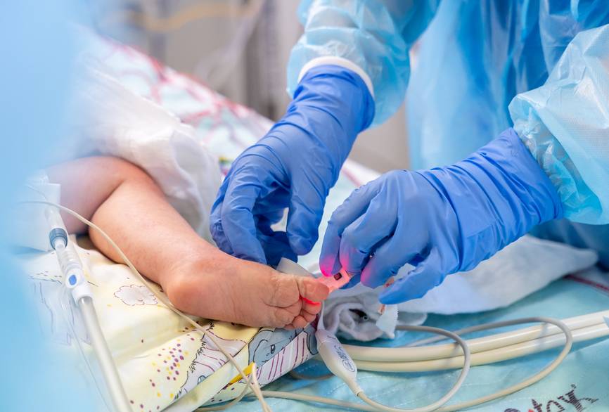 Pflegekraft bearbeiten einen Fuß eines Neugeborenen.