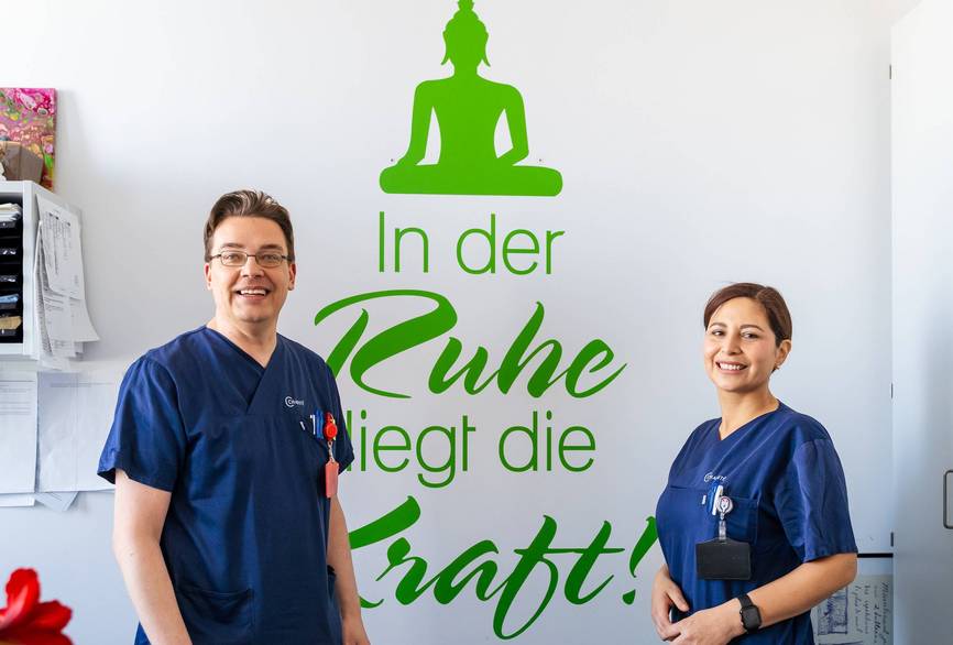 Jan und Paloma, zwei Pflegekräfte der Station M117 im Büro stehend.