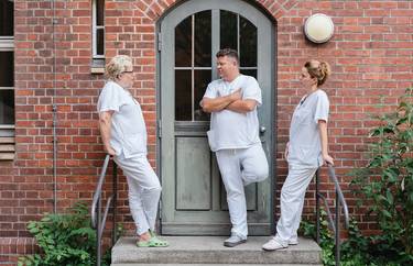 3 Pflegekräfte stehen unmittelbar vor dem Klinikgebäude und führen ein Gespräch in ihrer Pause