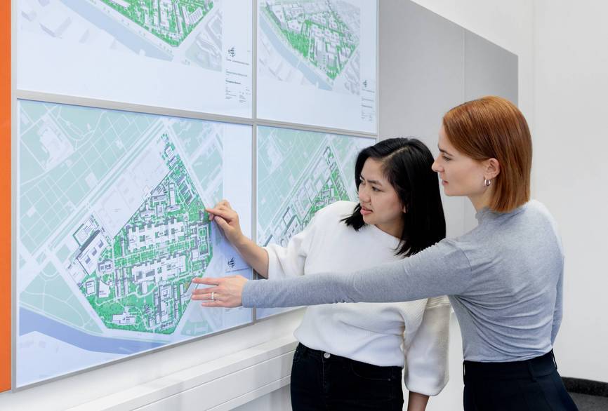 Zwei Mitarbeiterinnen aus dem Nachhaltigkeitsteam schauen sich gemeinsam einen Gebäudeplan der Charité an.