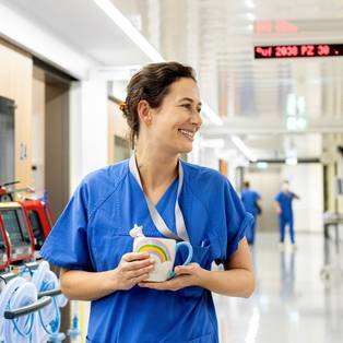 Eine Ärztin mit einer Einhorntasse in der Hand steht auf dem Flur einer neurologischen Intensivstation der Charité
