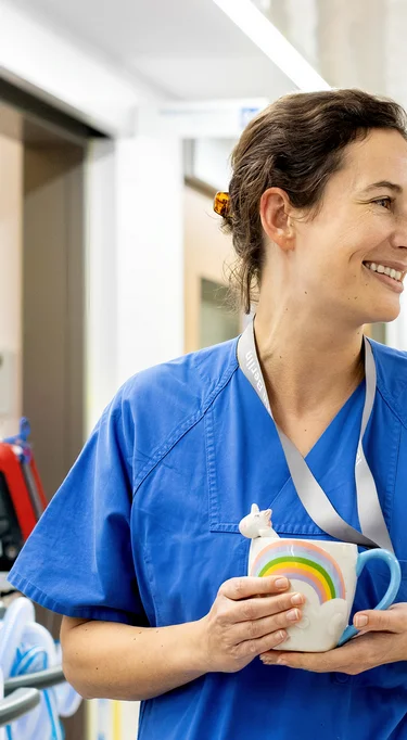 Eine Ärztin mit einer Einhorntasse in der Hand steht auf dem Flur einer neurologischen Intensivstation der Charité