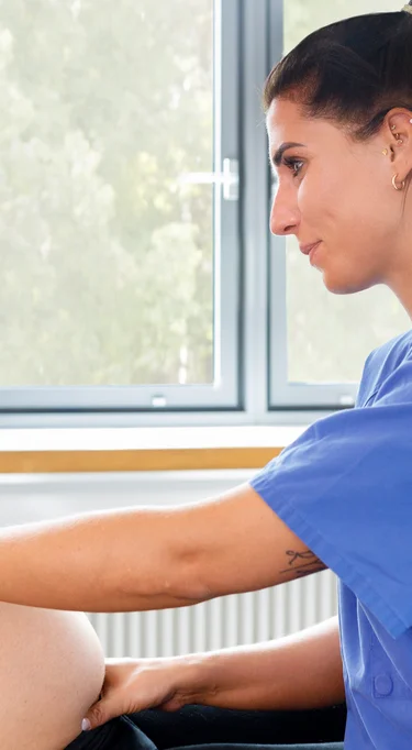 Eine Hebamme führt an einer schwangeren Frau den Leopoldgriff durch.