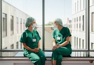 2 OP-Mitarbeiterinnen während der Pause, sitzend auf der Fensterbank