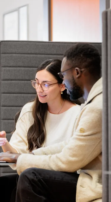 Zwei Mitarbeitende sitzen zusammen und besprechen sich.
