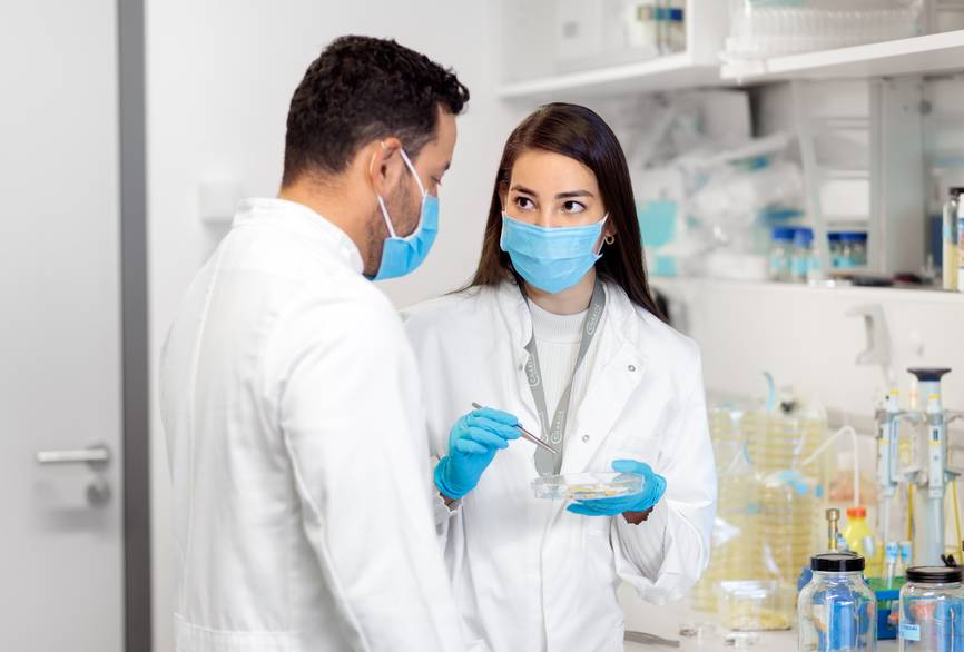 Zwei Forschende stehen in einem Labor und besprechen sich.