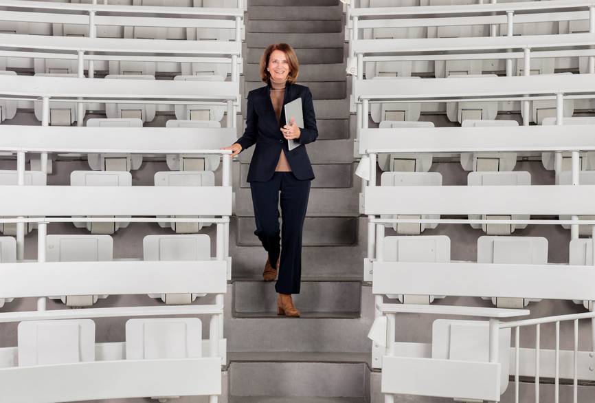 Eine Professorin geht die Stufen im Mittelgang eines Charité Hörsaals hinab.