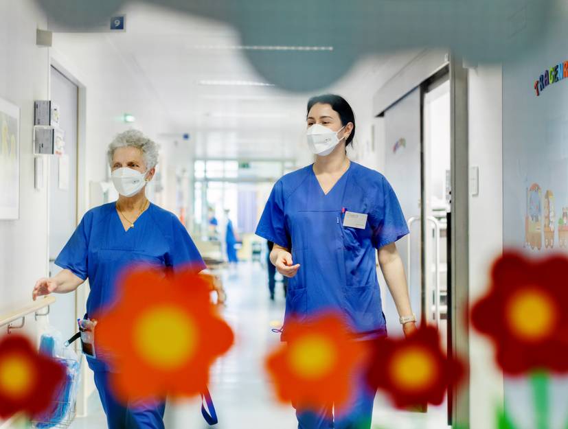 Zwei Pflegerinnen laufen den Gang der Kindernotaufnahme entlang. Im Vordergrund sind Blumen-Aufkleber zu sehen