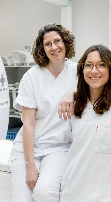 2 Mitarbeiterinnen der Radiologie stehen vor einem Kernspinntomographen
