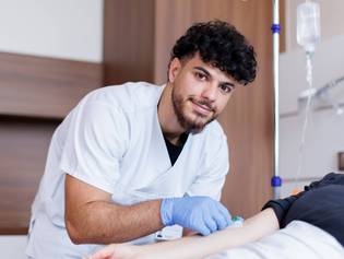 Ein Auszubildender im Bereich Pflege am Patienten.