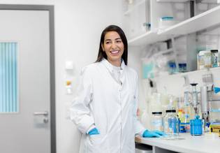 Eine Forscherin steht in einem Labor der Charité und lächelt.