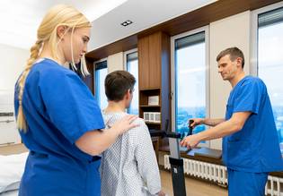 Therapie_Zwei Therapeut:innen (in blau) mit Patient