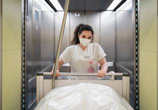 Eine Krankenpflegerin schiebt ein Bett aus dem Aufzug