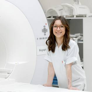 Eine Mitarbeiterin der Radiologie steht an einem Magnetresonanztomographen