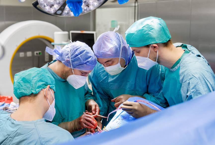 Ein Team von Ärzten steht um einen OP-Tisch und operiert