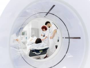 2 Mitarbeitende der Radiologie bereiten einen Patienten auf die Untersuchung im Magnetresonanztomographen vor