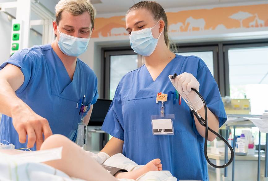 Zwei Pflegekräfte begutachten ein Neugeborenes.