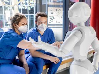 2 Pflegekräfte bedienen den Roboter Pepper auf der Kinderstation