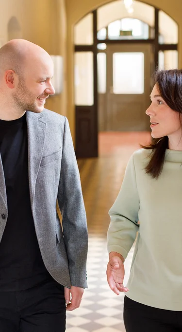 Zwei Mitarbeiter der Verwaltung bei einer Besprechung auf dem Flur der Charité