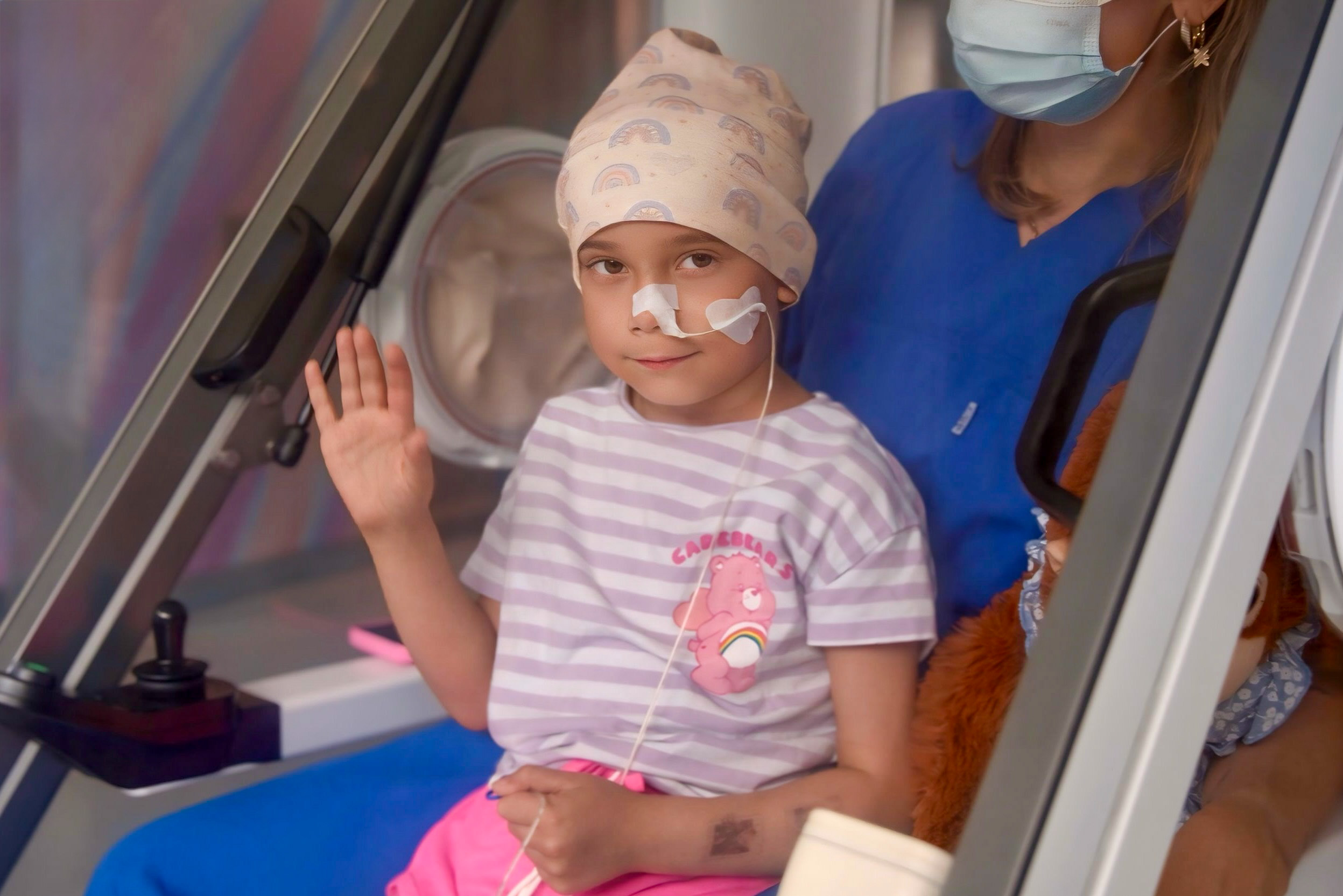 Charite Station 39i zwei Personen sitzen im Moby Car, das Kind winkt und lächelt