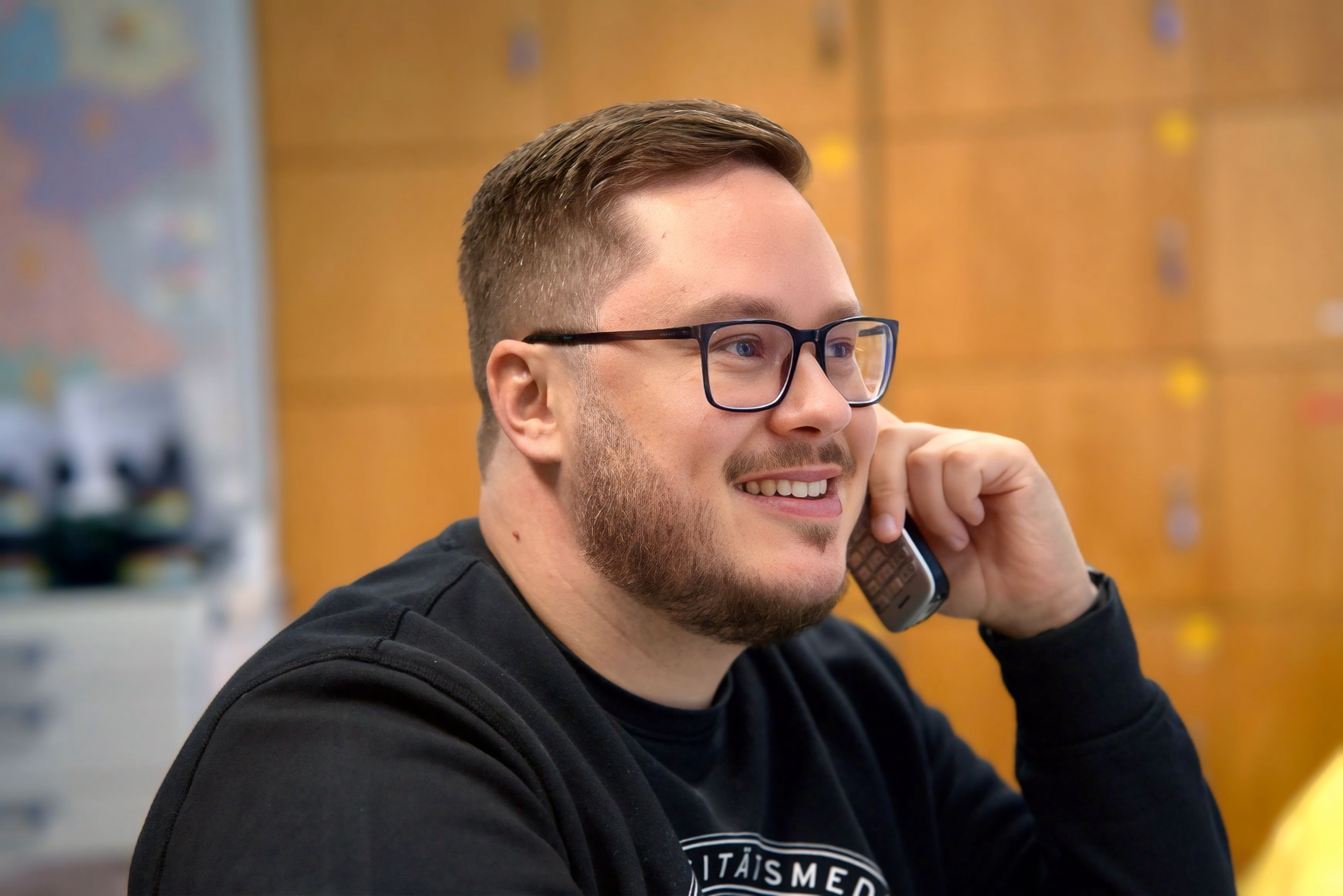 Charité Pflegefachkraft und Zentraler Praxisanleiter Pascal Hunger lächelnd am Telefon im Gespräch