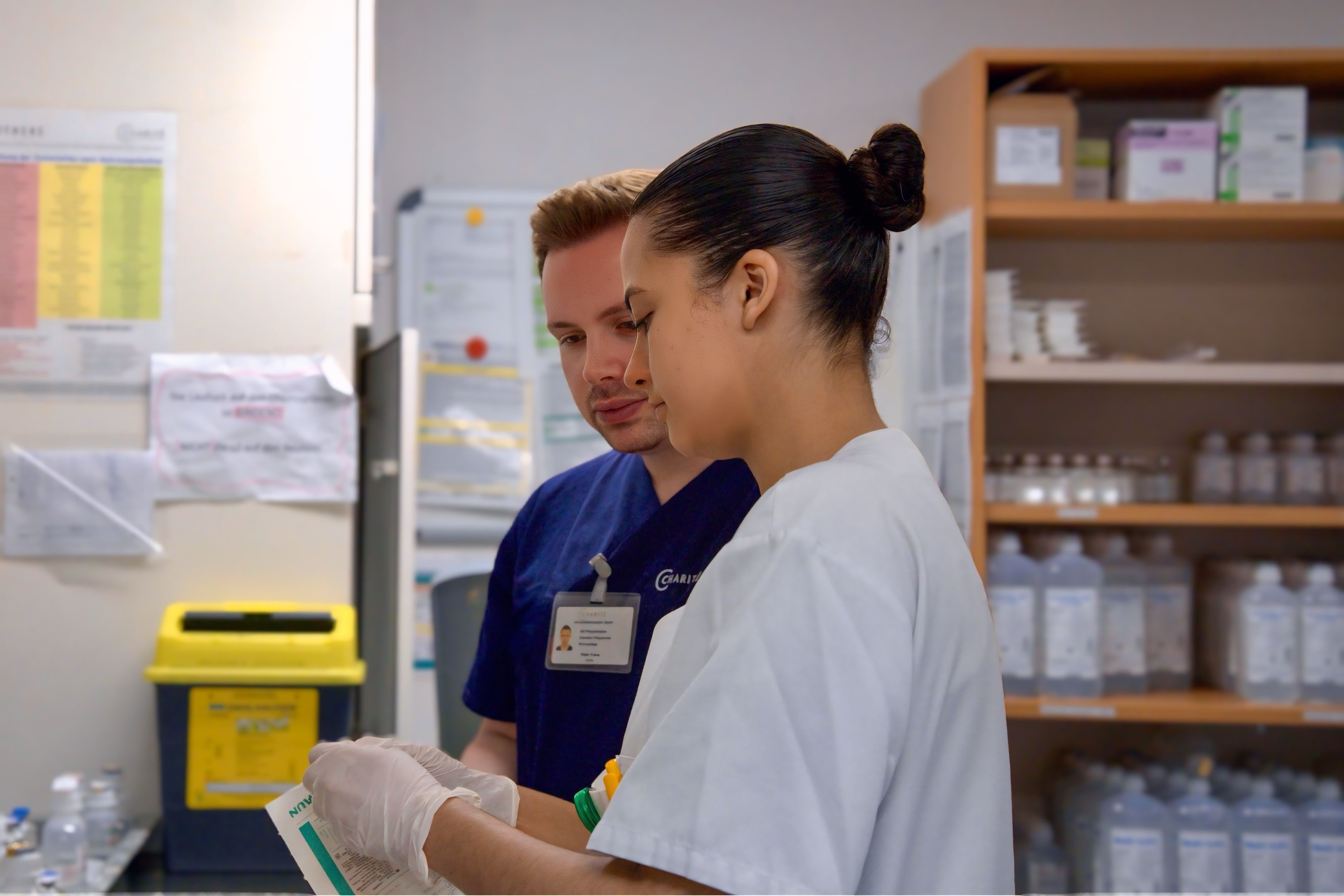 Charité Pflegefachkraft Peter aus dem Pflegepool mit Auszubildender im reinen Arbeitsraum